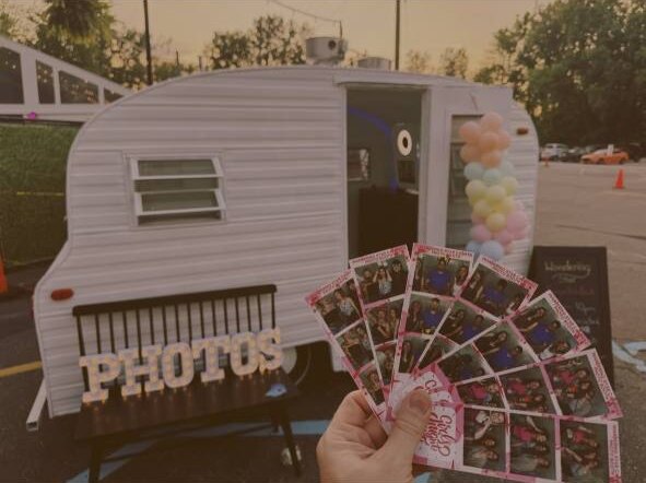 Personalized photo booth strips displayed in front of the vintage mobile camper